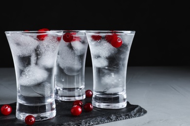 Vodka in shot glasses and cranberries on grey table