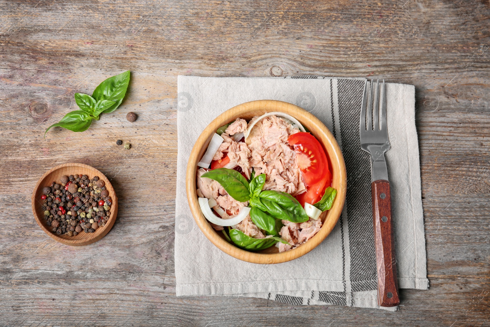 Photo of Delicious salad with canned tuna in bowl on wooden background, top view