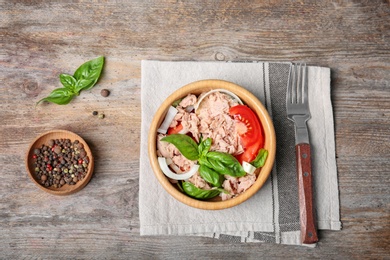 Delicious salad with canned tuna in bowl on wooden background, top view