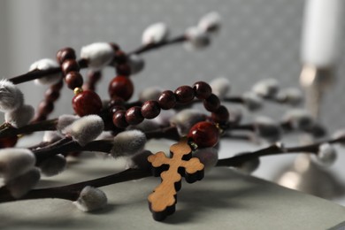 Photo of Rosary beads, willow branches and book on table, closeup