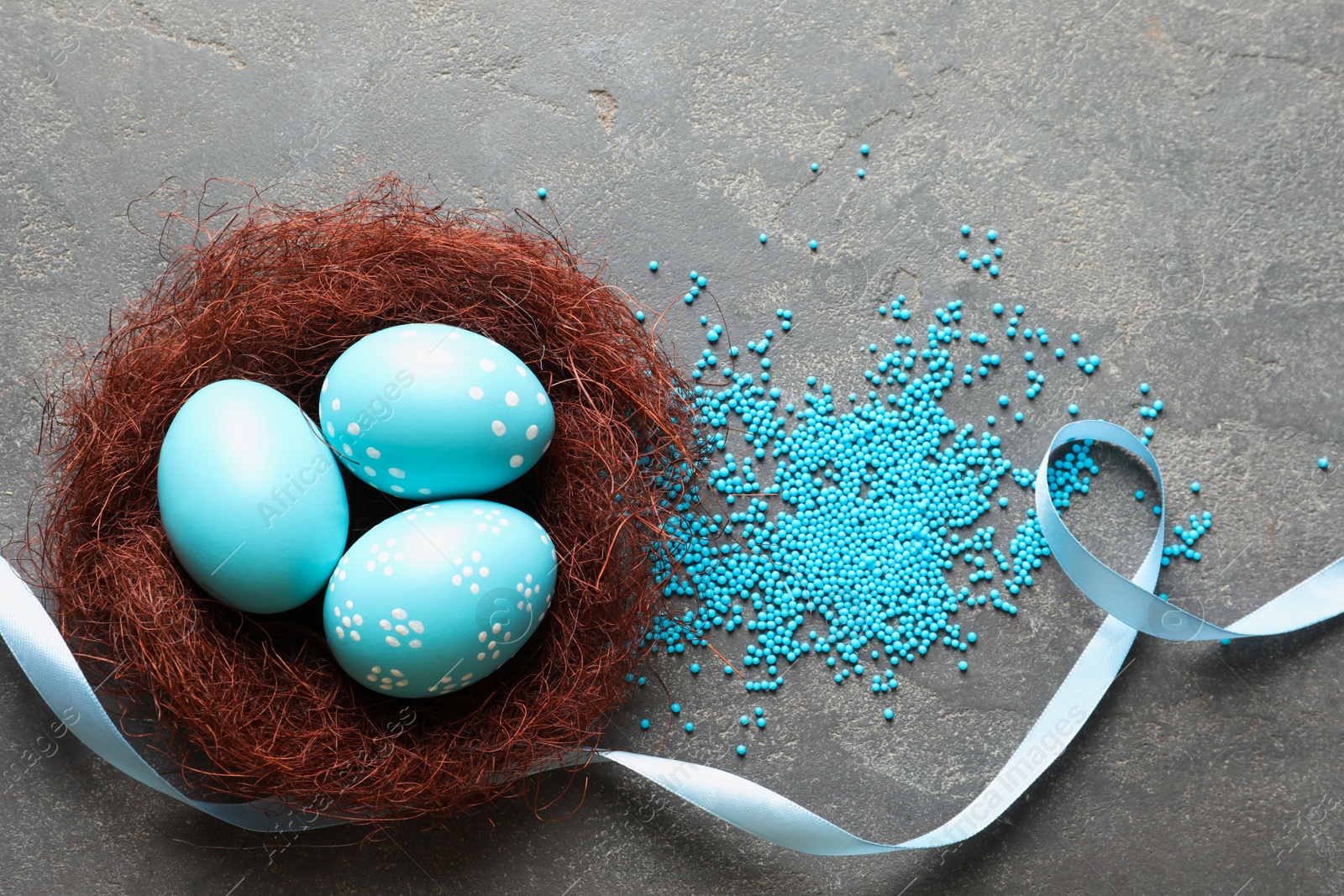 Photo of Flat lay composition with painted Easter eggs in sisal nest on color background, space for text