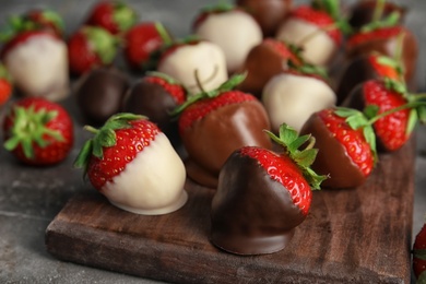 Photo of Chocolate covered strawberries on wooden board, closeup