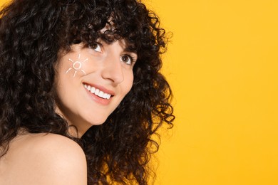 Beautiful happy woman with sun protection cream on her face against orange background, space for text