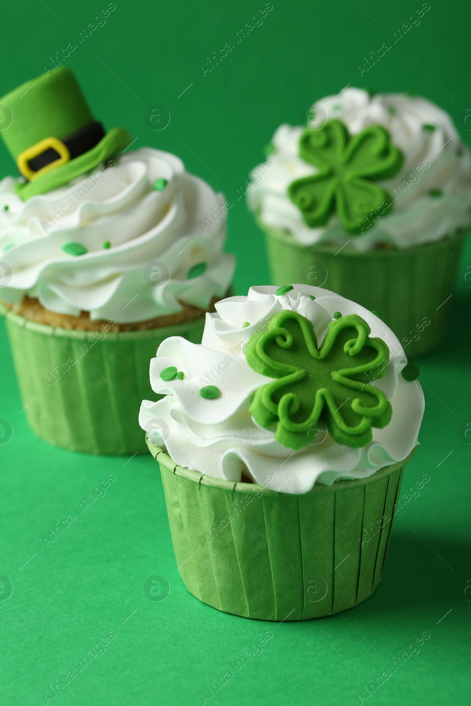 Photo of St. Patrick's day party. Tasty festively decorated cupcakes on green table, closeup