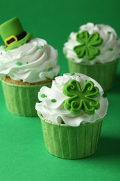 St. Patrick's day party. Tasty festively decorated cupcakes on green table, closeup