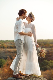 Photo of Happy newlyweds with beautiful field bouquet outdoors