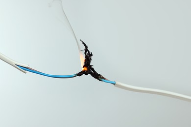 Inflamed white wire on grey background, closeup. Electrical short circuit