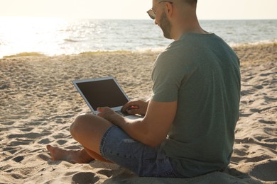 Photo of Man working with modern laptop on beach, closeup