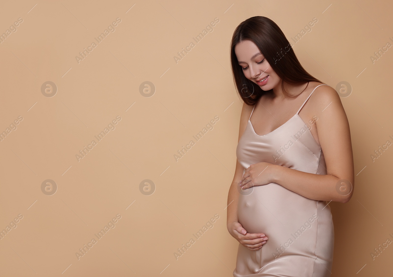 Photo of Beautiful pregnant woman in dress on beige background, space for text