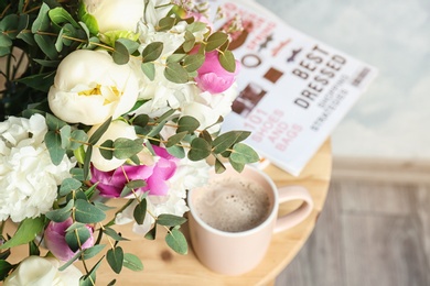 Photo of Bouquet with beautiful flowers and cup of coffee on table