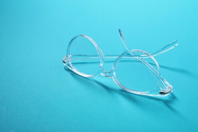 Stylish pair of glasses on light blue background, closeup