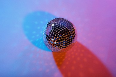 Photo of Bright shiny disco ball on color background