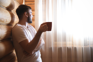 Photo of Man with drink near window indoors. Lazy morning