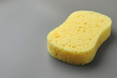 Photo of New yellow sponge on grey background, closeup. Space for text