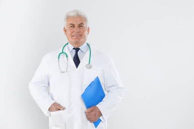 Photo of Portrait of senior doctor with stethoscope and clipboard on white background