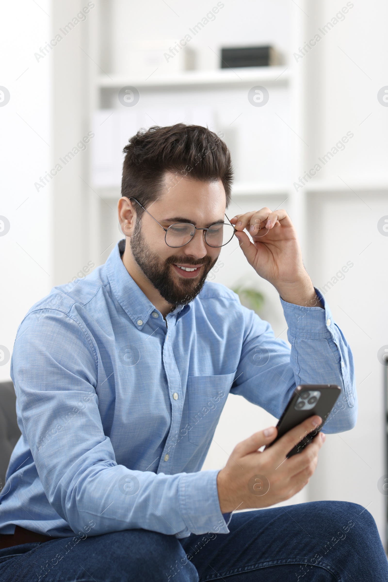 Photo of Handsome young man using smartphone in office