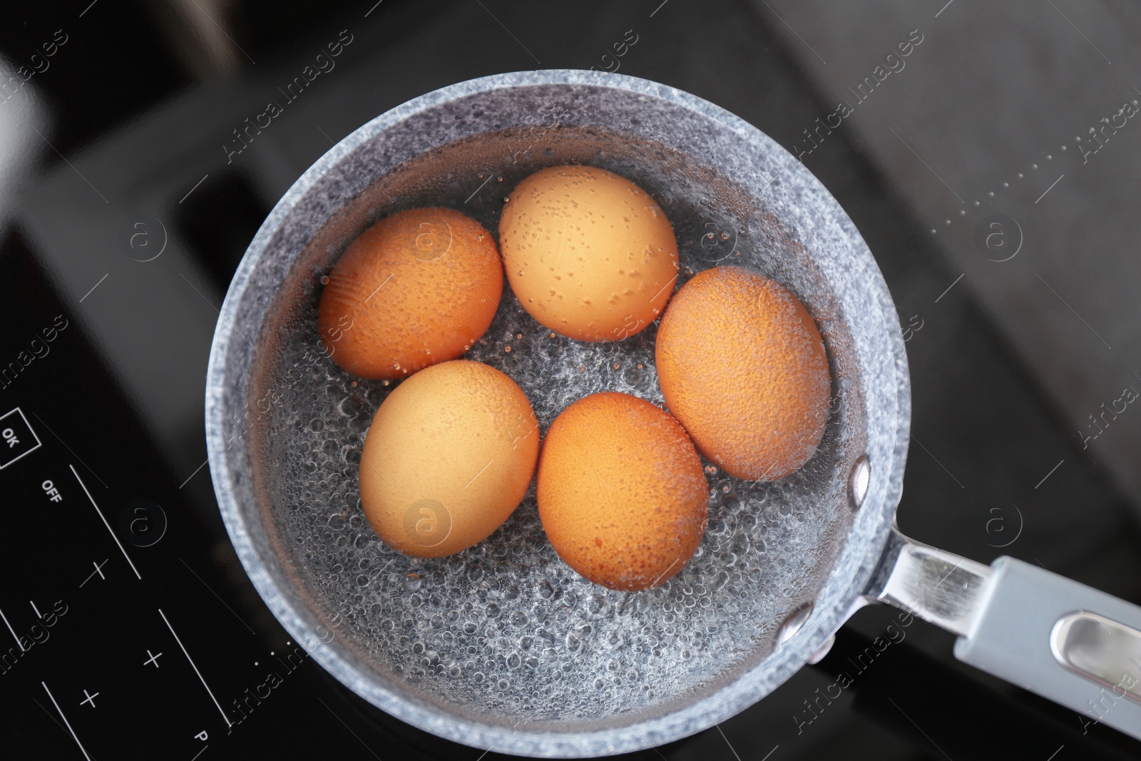 Photo of Chicken eggs boiling in saucepan on electric stove, top view