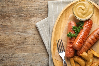 Photo of Flat lay composition with delicious grilled sausages on wooden table, space for text. Barbecue food