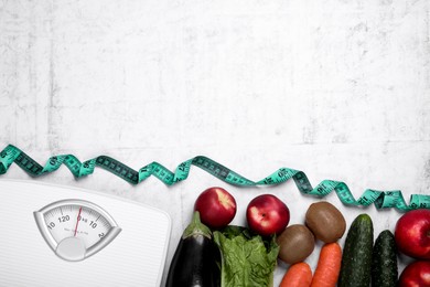Photo of Scales, measuring tape, fresh fruits and vegetables on light gray textured table, flat lay with space for text. Low glycemic index diet