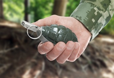 Soldier holding hand grenade in forest, closeup