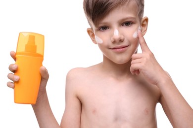Smiling boy applying sun protection cream on white background