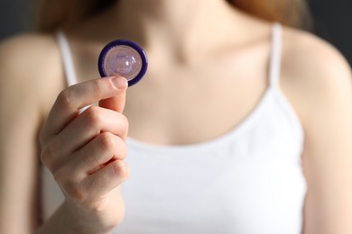 Photo of Woman holding unpacked condom, closeup. Safe sex