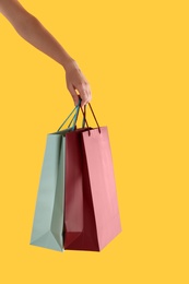 Photo of Woman with paper shopping bags on yellow background, closeup