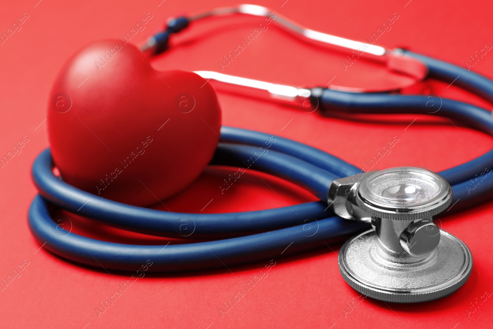 Photo of Red heart with stethoscope on color background, closeup