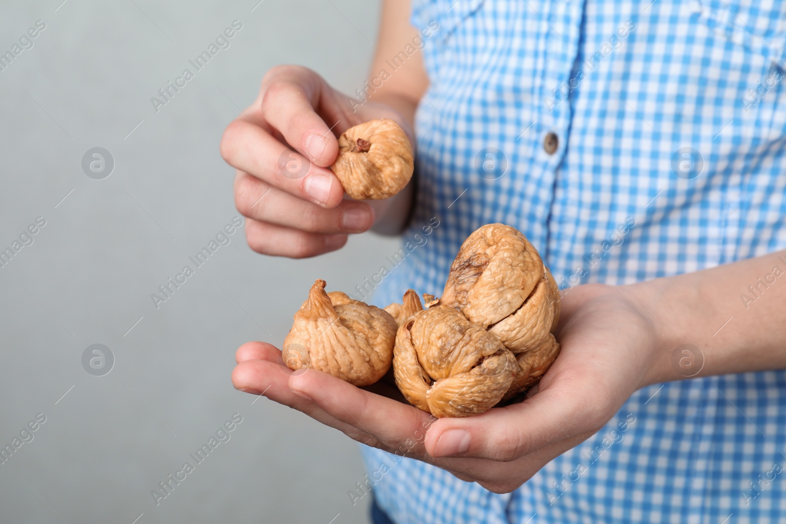 Photo of Woman holding handful of dried figs on light background, space for text. Healthy fruit