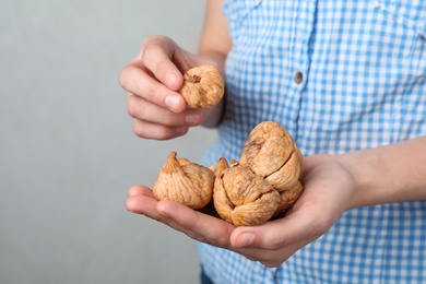 Photo of Woman holding handful of dried figs on light background, space for text. Healthy fruit