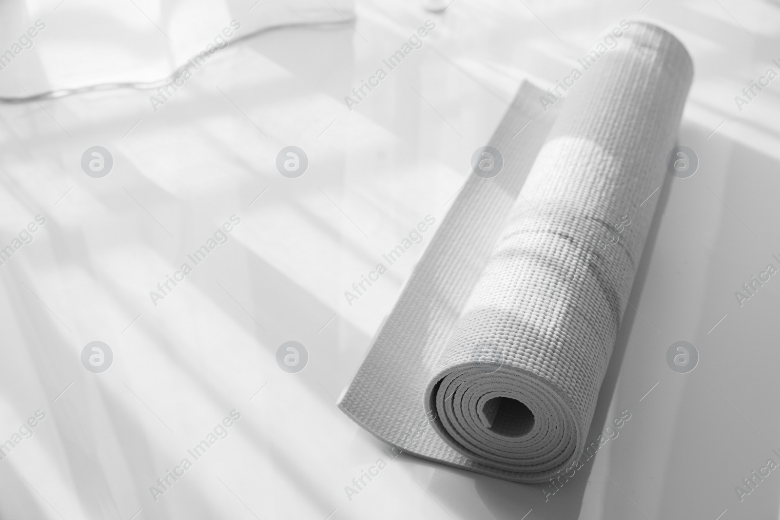 Photo of Rolled karemat or fitness mat on floor indoors, space for text