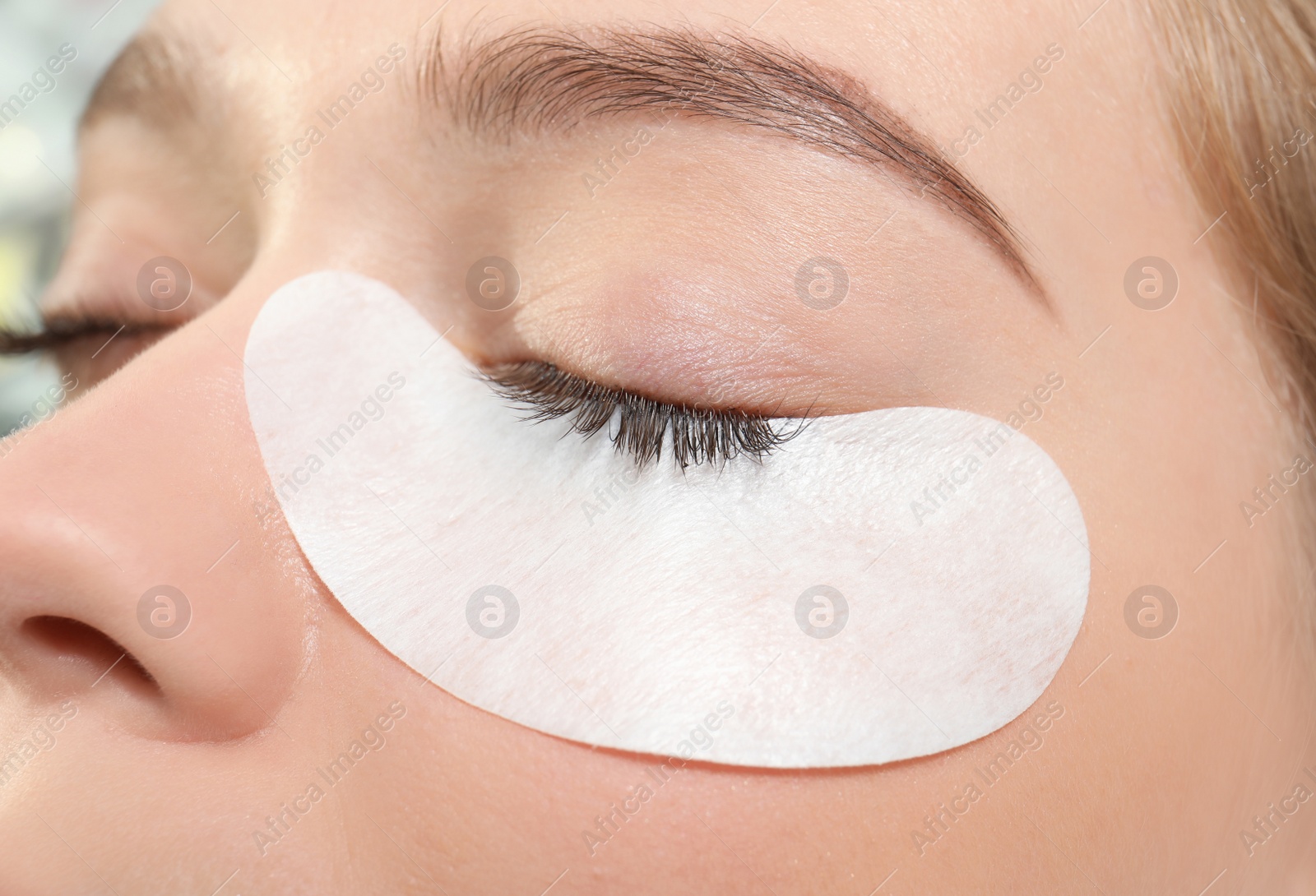 Photo of Young woman undergoing eyelash extension procedure, closeup