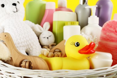 Photo of Different baby cosmetic products and accessories in wicker basket, closeup view