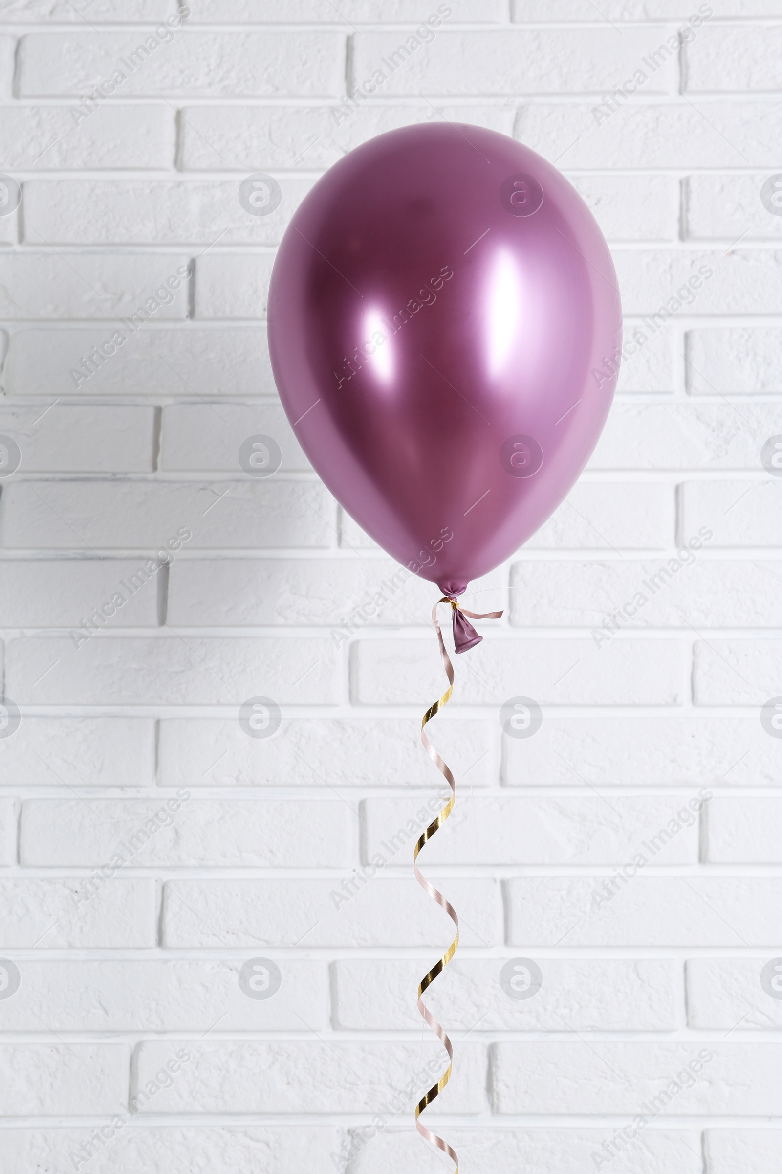 Photo of Bright balloon near brick wall. Party time