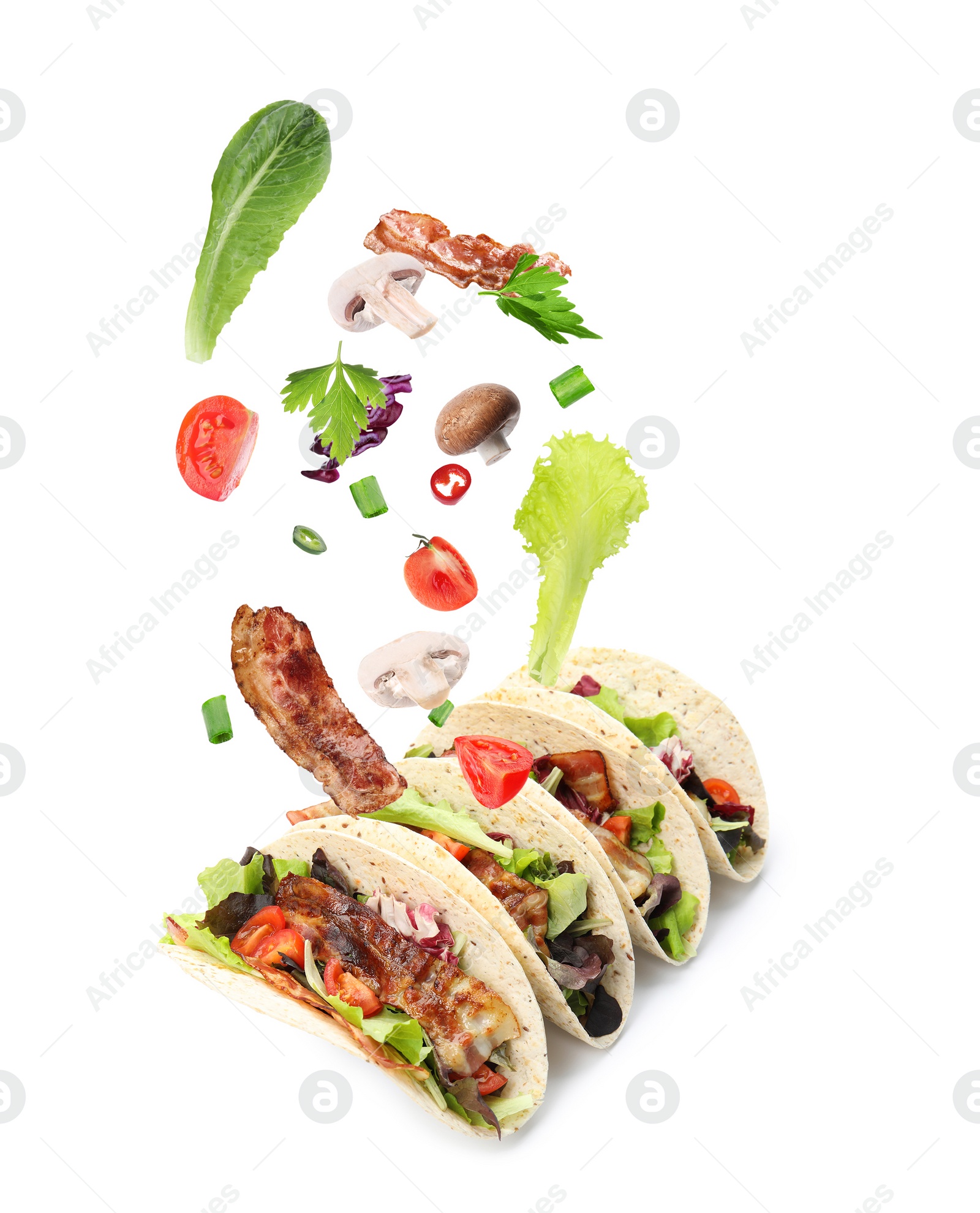 Image of Delicious tacos. Ingredients falling into tortillas on white background