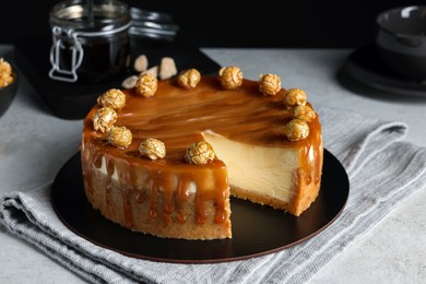 Sliced delicious cheesecake with caramel and popcorn on light grey table