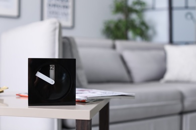 Photo of Analog alarm clock on table in living room. Time of day