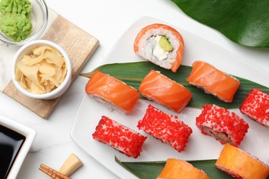 Flat lay composition with delicious sushi rolls on white marble table