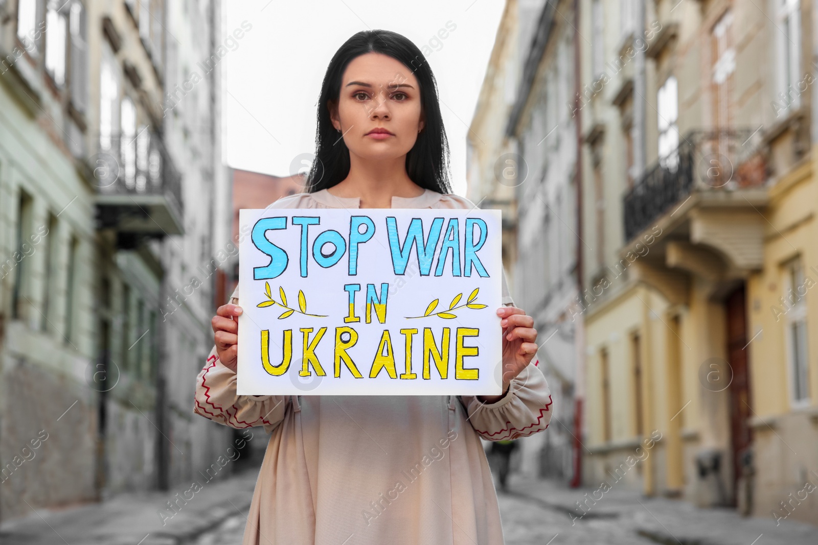 Photo of Sad woman holding poster Stop War in Ukraine on city street