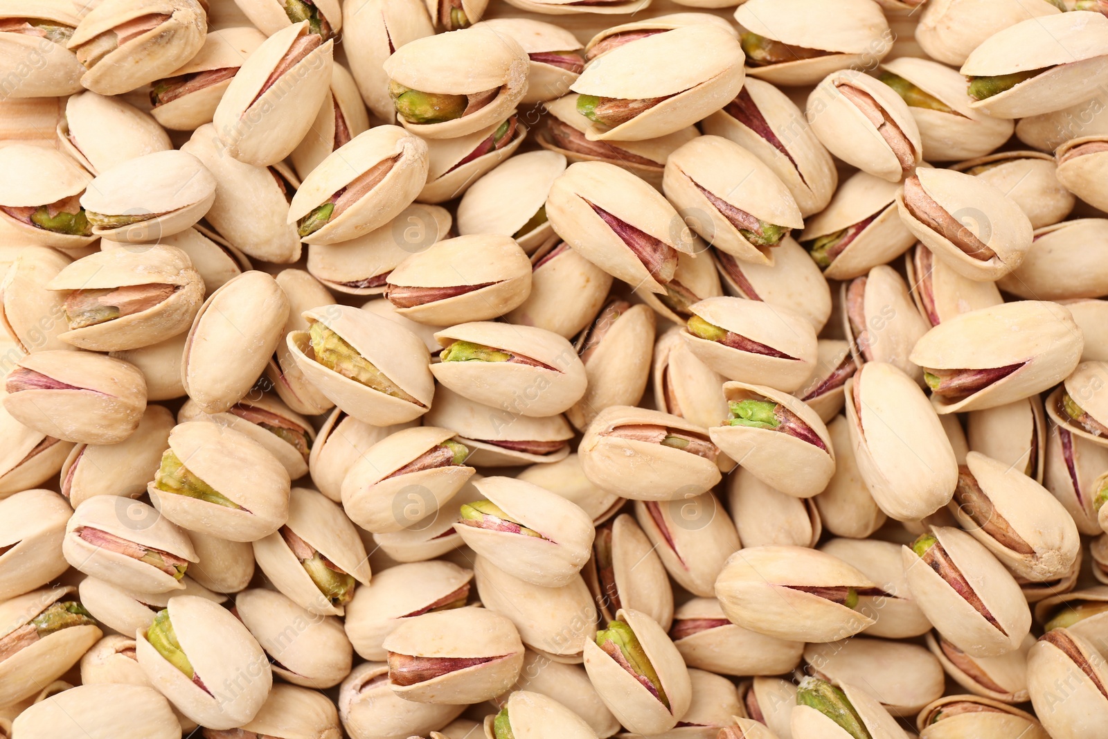 Photo of Tasty unpeeled pistachios as background, top view