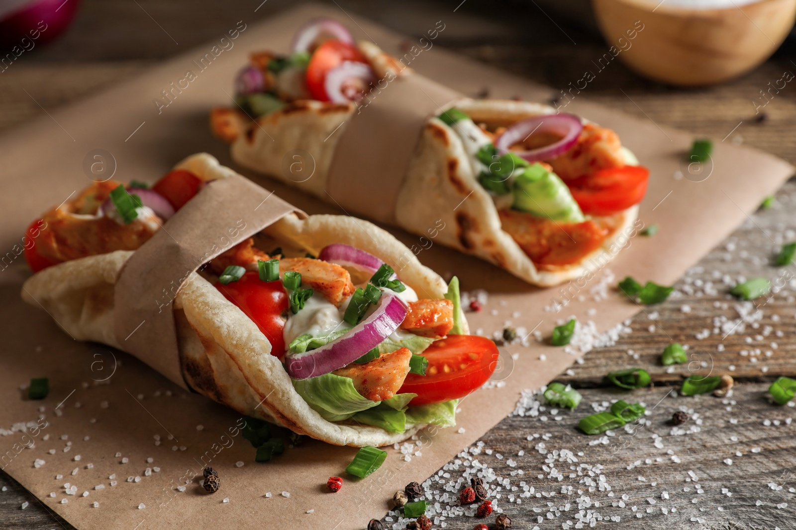 Photo of Delicious pita wraps with meat and vegetables on wooden table, closeup