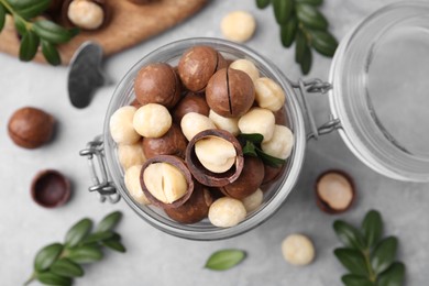 Tasty Macadamia nuts in jar on light grey table, flat lay