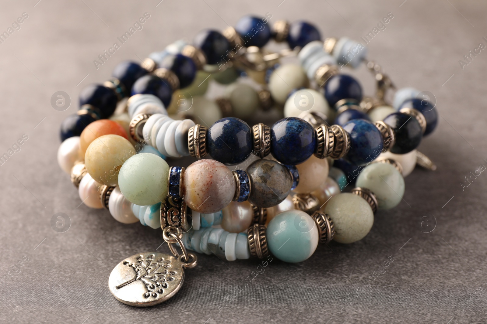 Photo of Beautiful bracelets with gemstones on grey background, closeup