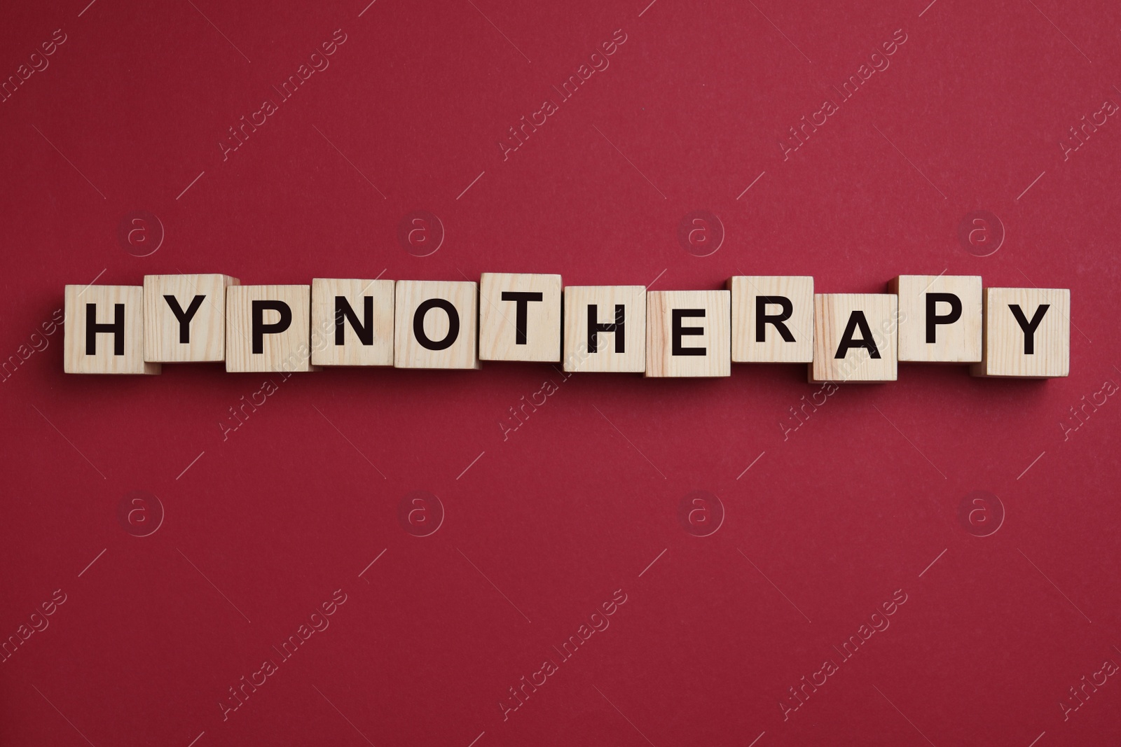 Photo of Wooden blocks with word HYPNOTHERAPY on red background, flat lay