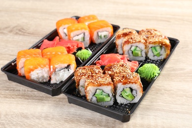 Boxes with tasty sushi rolls on wooden table. Food delivery