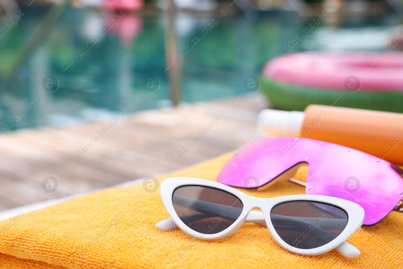 Photo of Beach towel and sunglasses near outdoor swimming pool at luxury resort, closeup. Space for text