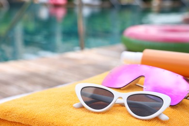 Photo of Beach towel and sunglasses near outdoor swimming pool at luxury resort, closeup. Space for text