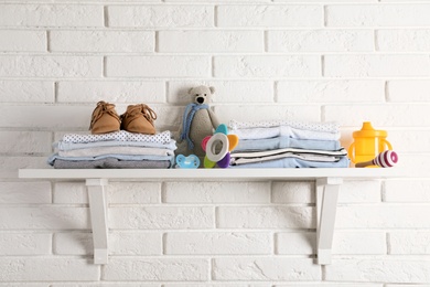 Photo of Shelf with baby accessories on white brick wall
