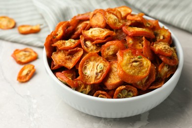 Bowl with cut dried kumquat fruits on white marble table, closeup