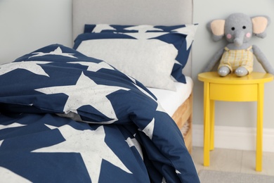 Bed with star patterned linens in child's bedroom. Interior design